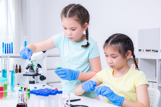 Asian girl and Caucasian girl concentrate on pipette handling and color preparation with teamwork, smart kids, interactive classroom, Science education experiment, chemistry laboratory research