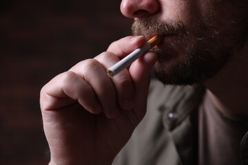 Man smoking cigarette on blurred background, closeup