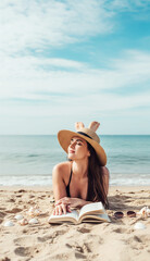 Relaxed Woman Reading Book on Sandy Beach in Straw Hat