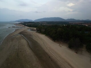 Beach landscape with hills and rock formations during noon and sunset