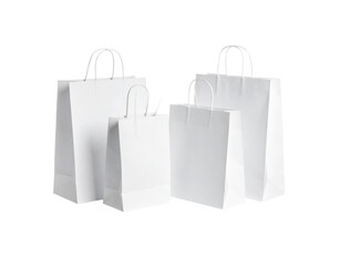Group of four white paper carrier bags large and small with twisted handles for shopping or gifts.