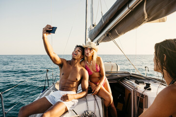 Tourists taking selfie on sailboat during summer vacation, enjoying friendship and adventure at sea