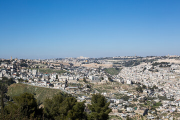 Panoramic view of Jerusalem, Israel with the historic Old City, Dome of the Rock, and surrounding residential neighborhoods under clear blue sky.