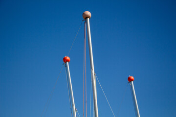 Sailing Masts with Red Finials Against a Blue Sky