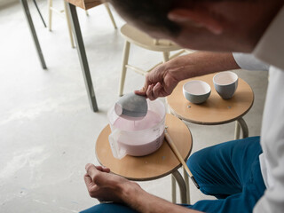 Potter working with pottery wheel and glazing tools during ceramic finishing process in pottery studio