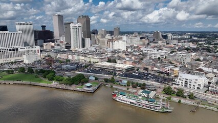 Aerial drone view of downtown New Orleans, Louisiana city city skyline office towers beside the Mississippi River with sunshine and fluffy clouds during a summer heat wave