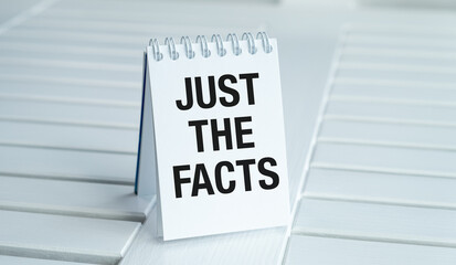 A white spiral bound notebook with the words Just the Facts written on it