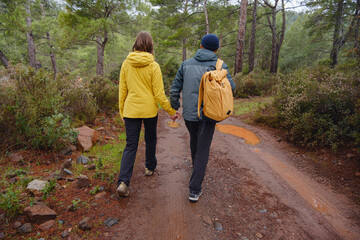 Fototapeta premium Couple enjoys Turkish coastline near Kemer. in pine forest. Sitting on stones, watching sea waves, relaxing together, slow romantic moment near calm blue water under soft winter light.