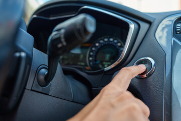 Close-up of hand pressing start button to turn on car engine. Keyless ignition system in modern car