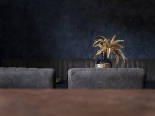 Golden decorative palm arrangement in ceramic vase on dark wooden dining table with grey...