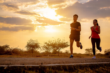 Silhouette of young couple running together on road across the bridge. Couple, fit runners fitness runners during outdoor workout