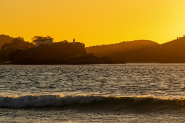 Beautiful sunrise at Praia do Forte, the sun rising next to the fort, behind the mountains. Cabo...