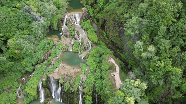 Italy, Umbria, Spectacular drone view of the Marmore Falls with water falling from above in a natural setting of unique beauty with pools of green water immersed in the lush nature