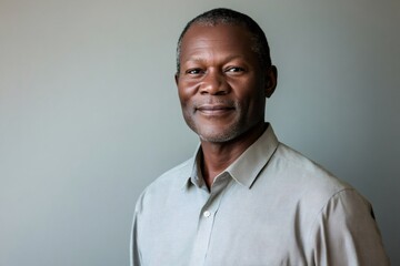 Fototapeta premium Studio portrait featuring a confident Jamaican businessman smiling warmly against a gray background, exuding professionalism and leadership