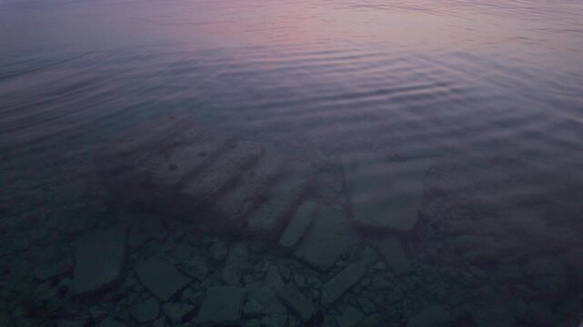 Abandoned concrete stairs under the water on the Haludovo Beach in Malinska - Krk Island, Croatia in beautiful sunset lights. There are some sea urchins on the ghost stairs. Paradise trail highlights.