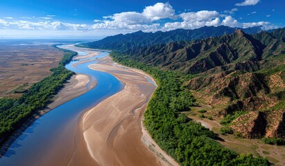 The winding Yellow River flows through the desert, with mountains in the background and a clear blue sky
