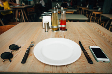 Empty plate waiting for pizza and cold drinks in restaurant