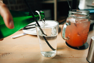 Waiter pouring refreshing drink into glass with straw in restaurant setting