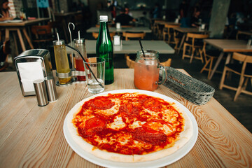 Delicious pepperoni pizza with cold drinks on restaurant table