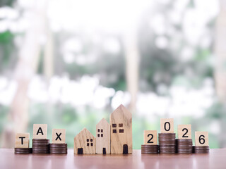 Miniature house, Wooden blocks with the word TAX and number 2026 on stack of coins. The concept of payment tax for house, Property investment, House mortgage, Real estate in year 2026