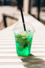 Refreshing green mint drink with ice on white table in outdoor cafe