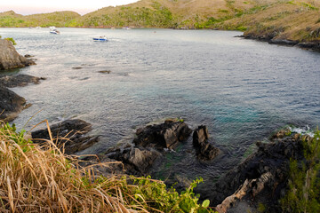 The beautiful beach at Forte São Mateus in Cabo Frio at the end of the afternoon, with many mountains around and rocks with sea water around them.