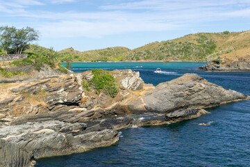 The beautiful beach of the fort around Forte São Mateus in Cabo Frio, with many rocks, the sea water running between them and mountains around.