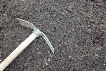 Pickaxe lying on fertile soil ready for gardening work