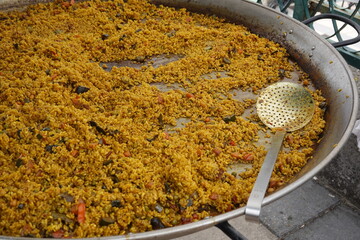 Large paella pan with serving spoon, cooking outdoors