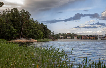 View of the mountain on the lake shore and cloudy sky on a summer day