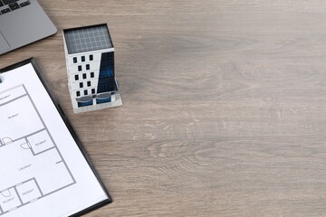 Real estate. Apartment building model, floor plan and laptop on wooden table. Space for text