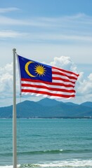 Malaysian Flag Waves Proudly by the Ocean Under a Sunny Sky: A Coastal View of Patriotism