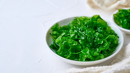 closeup heap of green laver ulva lactuca or sea lettuce seaweed in ceramic bowl on white table food background with copy space