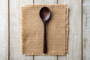 Dark wooden spoon on burlap fabric over white wood.