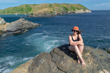 Woman enjoying the view from above the fort of Praia do Forte, many rocks, sky with clouds and a beautiful sea around.