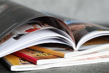 Stack of different magazines on grey table, closeup