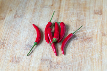 several fresh red chili peppers on a wooden surface