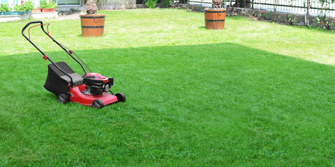 Lawn mower on lush bright green grass outdoors, banner design