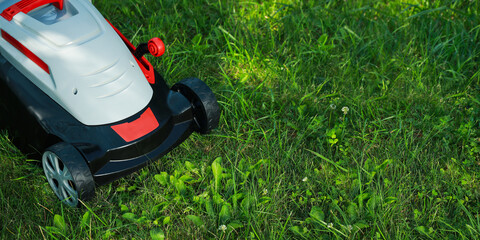 Lawn mower on lush bright green grass outdoors, banner design