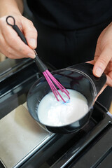 A black mixing bowl containing hair bleaching products held by a hairstylist. Ready for blending...