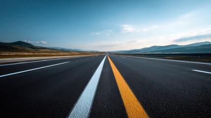 Fototapeta premium Wide Shot of Empty Modern Highway Road Lane Leading Toward Mountains Under Blue Sky.