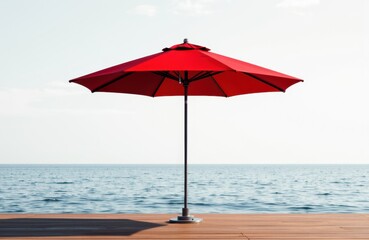 A red beach umbrella open on a wooden deck overlooking the ocean