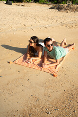 Fototapeta premium Couple lying on beach towel enjoying summer vacation