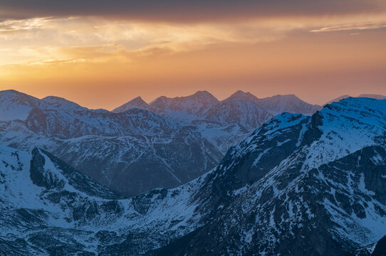 View of snow-capped mountain peaks pierced by the golden hues of the setting sun, casting long shadows across the serene landscape, Bia&Aring;&sbquo;ka Tatrza&Aring;&bdquo;ska, Wojew&Atilde;&sup3;dztwo ma&Aring;&sbquo;opolskie, Poland.