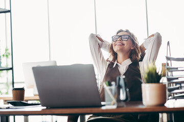 Young Professional Woman Relaxing in Modern Office with Laptop and Stylish Workspace During a...