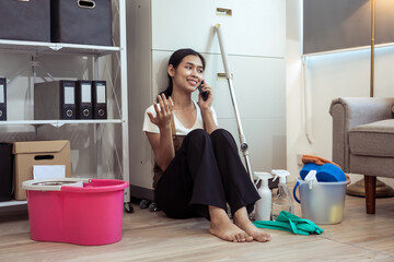 Young housekeeper wearing gloves and cleaning the table with a rag and cleaning spray. Professional...