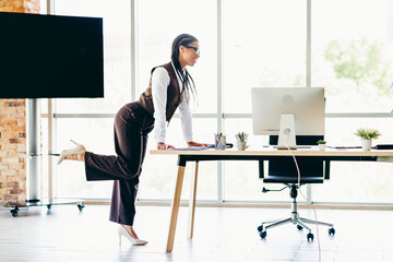 Confident businesswoman working at office desk, standing and reviewing project on desktop computer...