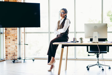 Professional businesswoman in stylish office work attire posing in a contemporary office...