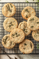 Shortbread cheese cookies with aromatic herbs on cooling rack on rustic textured background close...