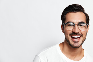 Happy smiling young caucasian man wearing glasses and a white t-shirt, looking at the camera with a...